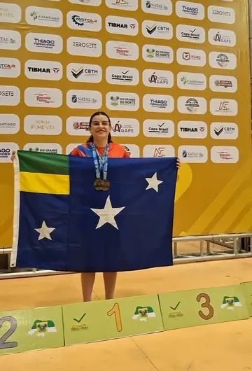 Atleta da ALMESC no pódio da Copa Brasil em Natal, com a medalha e a bandeira de Santa Catarina
